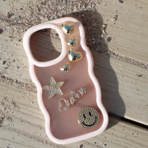 Rosa mobilskal med charms på trall.